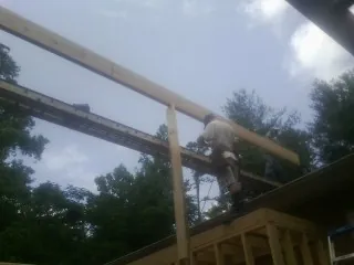 Carpenter setting a ridge beam over a new addition frame — Ice Dam Removal by Roofing Brothers in Saint Maries