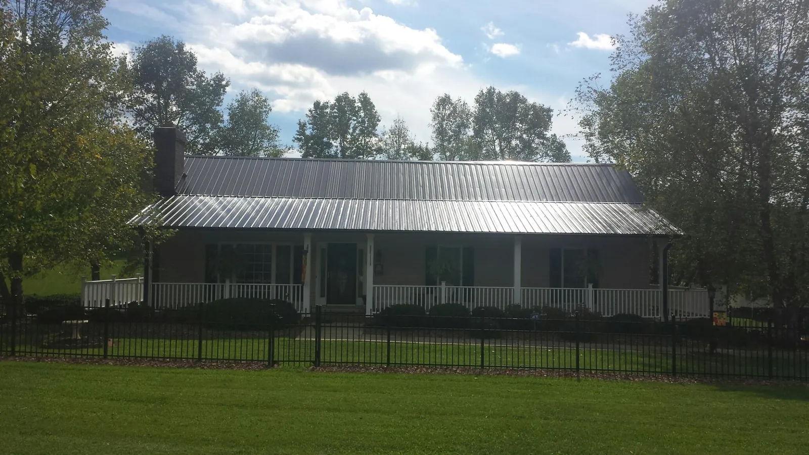 Gray metal roof on a brick ranch with a full width front porch — Gutter Guard Installation work by our crew in Saint Maries