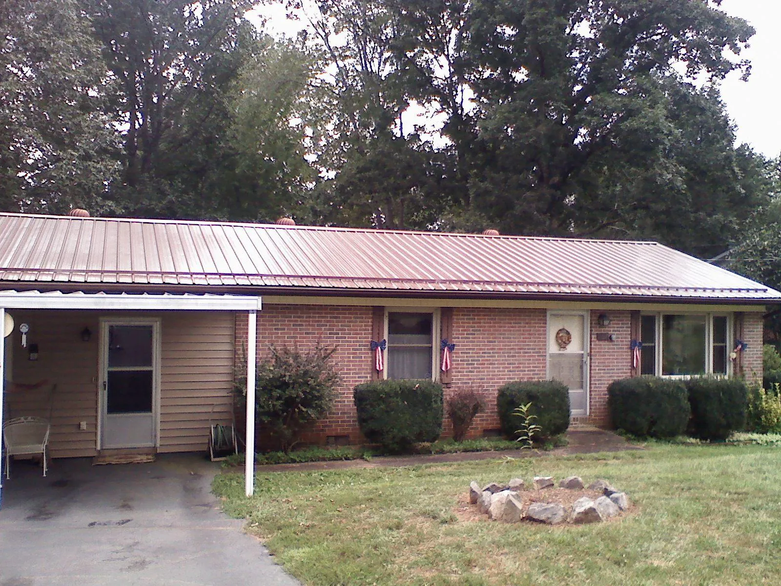 Bronze metal roof and carport on a brick ranch home — Roof Repair work by our crew in Saint Maries