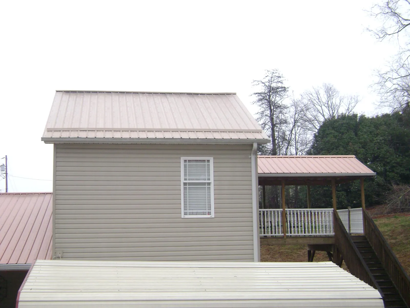 Tan metal roofs on a two story addition and attached porch, from a Roof Replacement job in Saint Maries
