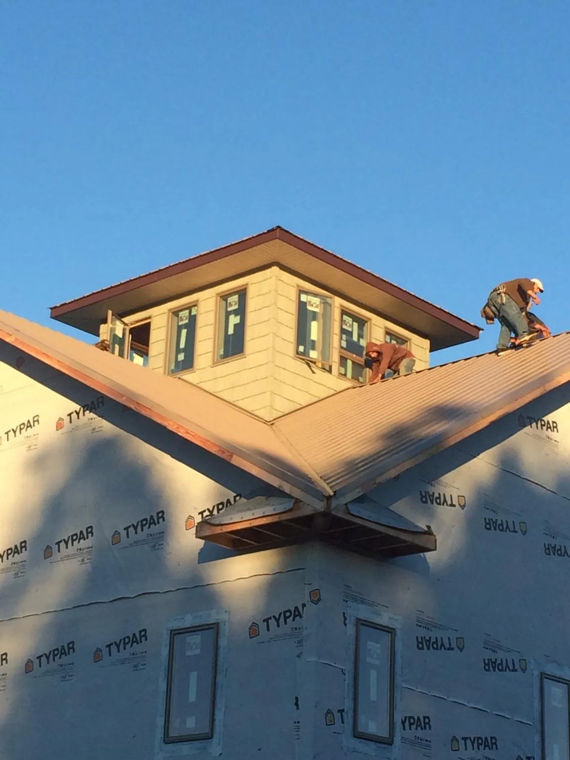 Roofers working around a rooftop cupola on a new metal roof at sunset — Roof Waterproofing in Saint Maries by Roofing Brothers